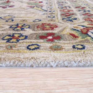 Close view of a thick-pile beige rug with colorful floral patterns resting on pale wood floor.