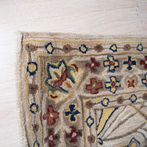 Textured beige rug detail featuring stylized floral and geometric patterns in blue, yellow, and red on light wood.