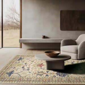 Ornate cream rug with blue, red, and yellow traditional patterns beneath a gray coffee table and armchair.