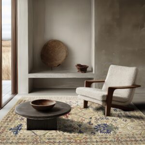 Traditional beige rug with colorful floral motifs grounds a modern space with a textured cream chair and dark table.