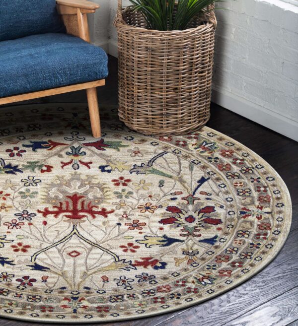 Beige round rug with red and blue traditional floral pattern next to a wicker planter and blue chair.