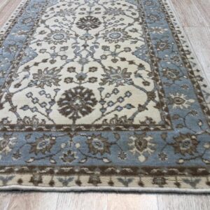 Cream runner rug featuring a traditional floral pattern and blue border on light wood planks.