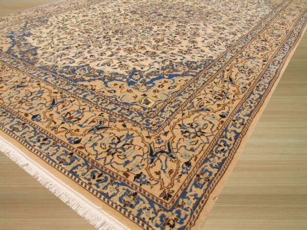 Angled view of a detailed beige and blue traditional rug featuring scrolling floral patterns on light wood flooring.