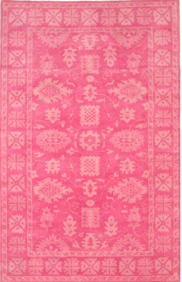 Bright pink rug featuring a monochromatic traditional floral and geometric border design.