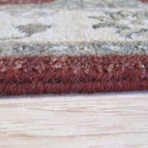 Thick, dark red rug edge next to a patterned cream area, resting on light wood flooring.