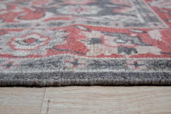 Textured medium pile rug in coral, gray, and cream sits on light wood plank flooring.