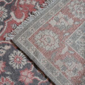 Close-up of a gray and coral rug, showing the dense patterned pile and the woven backside with fringe.