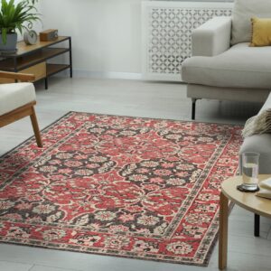 A red, black, and cream floral traditional rug anchors a neutral living room with light wood flooring.