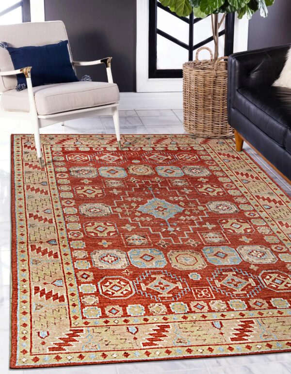 Rust-colored rug featuring beige and blue geometric motifs next to a cream armchair and black couch.