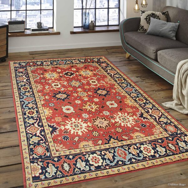 Rust and navy medallion rug defines a living area with a gray couch and large industrial windows.