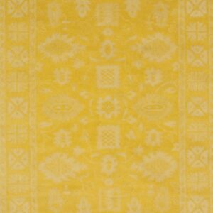 Bright yellow rug with a faded traditional pattern and distinct geometric borders.