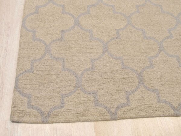A looped beige rug with a gray moroccan trellis pattern rests on pale wood flooring.