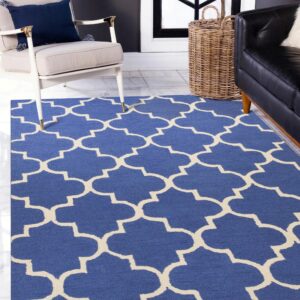Geometric blue and cream rug on marble tile floors next to a beige chair and black sofa.