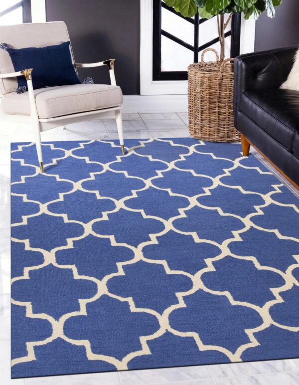 Geometric blue and cream rug on marble tile floors next to a beige chair and black sofa.