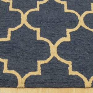 Close-up of a navy blue rug with a beige geometric trellis pattern on light wood flooring.