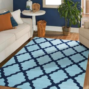 A light blue rug with a navy trellis pattern sits on hardwood floors between cream sofas in a blue room.
