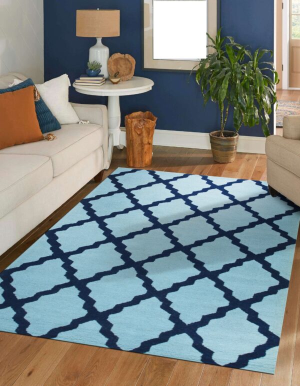 A light blue rug with a navy trellis pattern sits on hardwood floors between cream sofas in a blue room.
