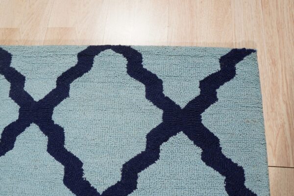 Light blue high-pile rug with a navy blue trellis pattern rests on natural wood flooring.