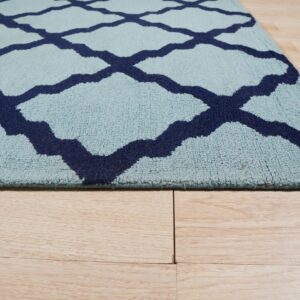 Light blue, medium-pile rug with a navy geometric trellis pattern rests on light wood plank flooring.