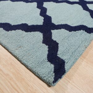 Light blue rug with navy trellis pattern and textured pile on natural wood plank flooring.