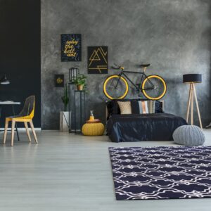 Navy and white patterned rug contrasts with light gray floors and dark gray textured walls.