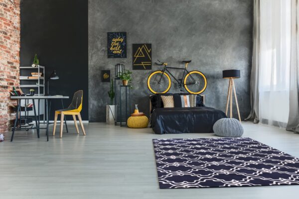 Navy and white patterned rug contrasts with light gray floors and dark gray textured walls.