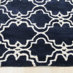 Navy blue rug with a white Moroccan trellis pattern rests on light wood flooring.