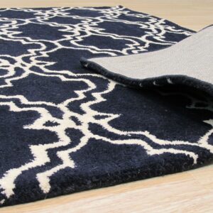 A navy high-pile rug with a cream trellis pattern is rolled back, showing the woven backing on light wood floors.