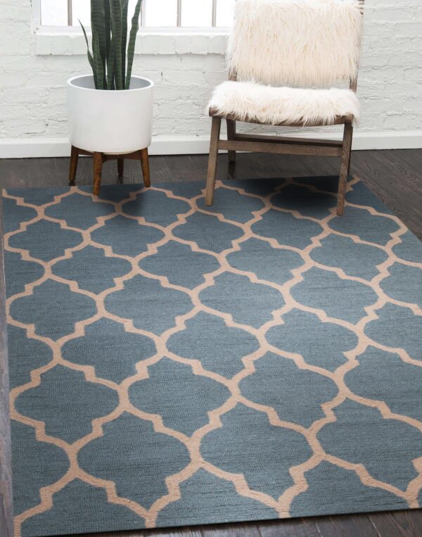 A blue and tan geometric rug on dark wood floors is bordered by a white planter and furry chair.