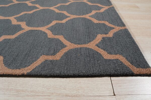 A textured gray rug with a light brown quatrefoil pattern rests on pale wood planks.