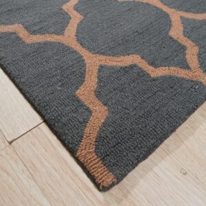 Textured gray rug with a tan geometric trellis pattern rests on light wood planks.