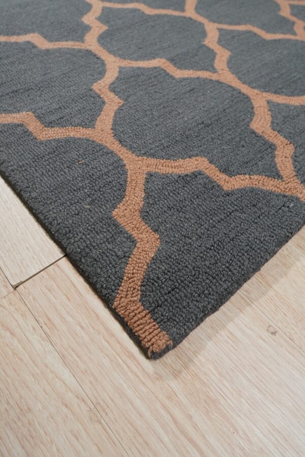 Textured gray rug with a tan geometric trellis pattern rests on light wood planks.