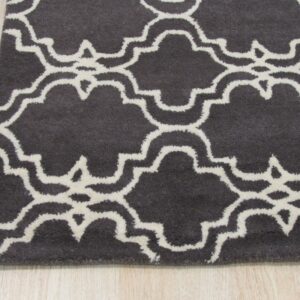 Close-up of a charcoal rug with a creamy white Moroccan quatrefoil pattern on light wood flooring.