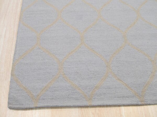 A textured light gray rug with a beige geometric trellis pattern lies on light wood flooring.