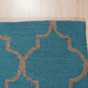 Textured teal rug with a tan geometric pattern rests on light wood plank flooring.