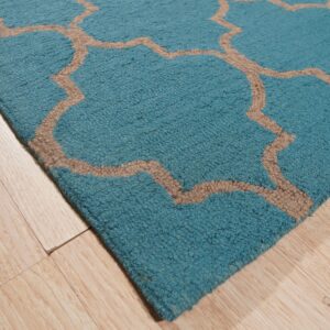 Textured teal rug with a tan geometric trellis pattern on light wood flooring.