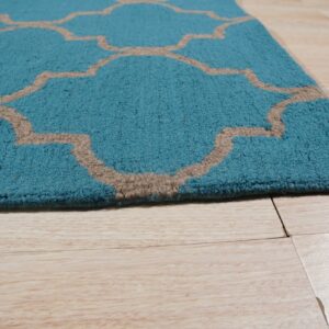 Teal rug with a textured tan quatrefoil pattern rests on light-colored wood plank flooring.
