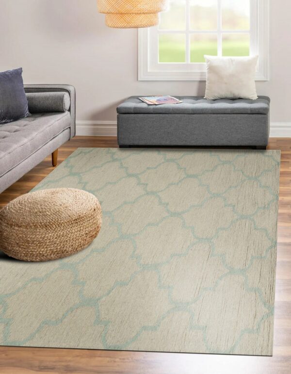 Beige rug with light blue trellis pattern covers wood floors beneath a gray sofa and storage bench.