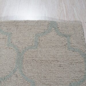A textured beige rug with a light gray-blue geometric pattern rests on light wood plank flooring.
