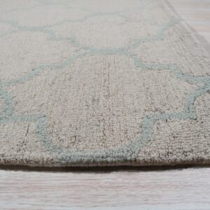 Textured, thick pile beige rug with a pale aqua trellis pattern on light wooden floorboards.