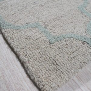 Textured beige rug with a pale blue geometric pattern rests on light wood grain flooring.