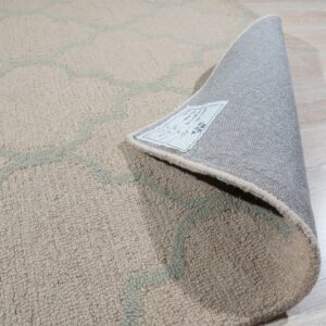 Textured beige and pale green rug shown curled back revealing the gray backing on light wood flooring.