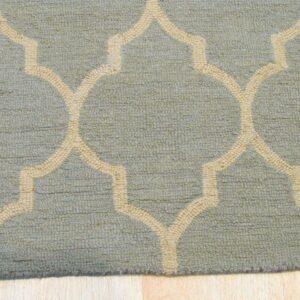 Close-up of a blue-green textured rug featuring a raised beige Moroccan trellis pattern on light wood floor.