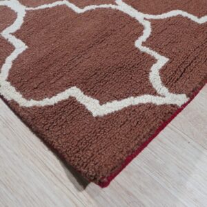 Rust and cream high-pile rug featuring a geometric trellis pattern over light wood flooring.