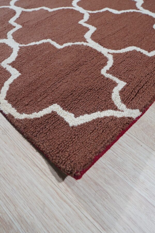 Rust and cream high-pile rug featuring a geometric trellis pattern over light wood flooring.