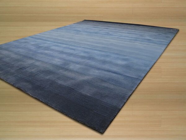 Blue rectangular rug featuring a horizontal gradient resting on light wood flooring.