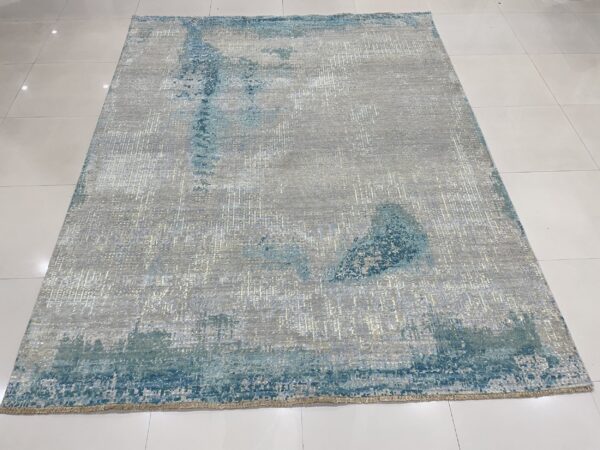 Distressed silver and gray rug with blue-green abstract accents rests on glossy light-colored tiles.