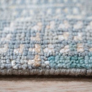 Knotted, medium-pile rug texture in blue, teal, and white abstract patterns on light wood.