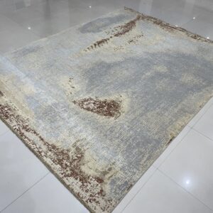 Abstract gray and cream rug with distressed brown accents on shiny white tile flooring.