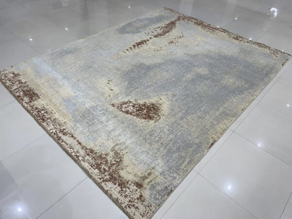 Abstract gray and cream rug with distressed brown accents on shiny white tile flooring.